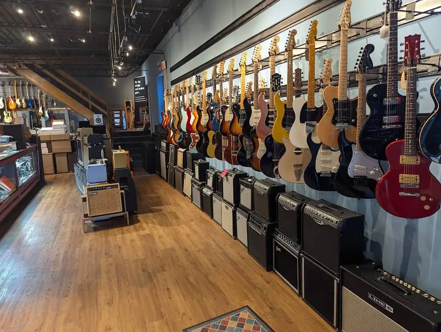 Inside the shop, guitars along the wall and amps down the aisle