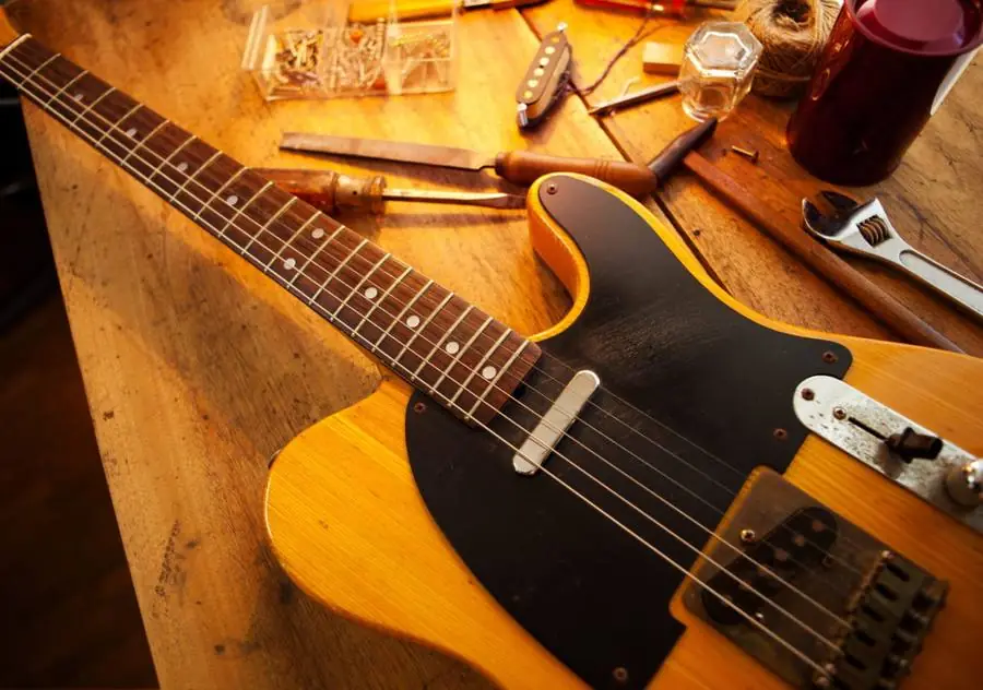 A guitar on the repair bench with tools laid out around it